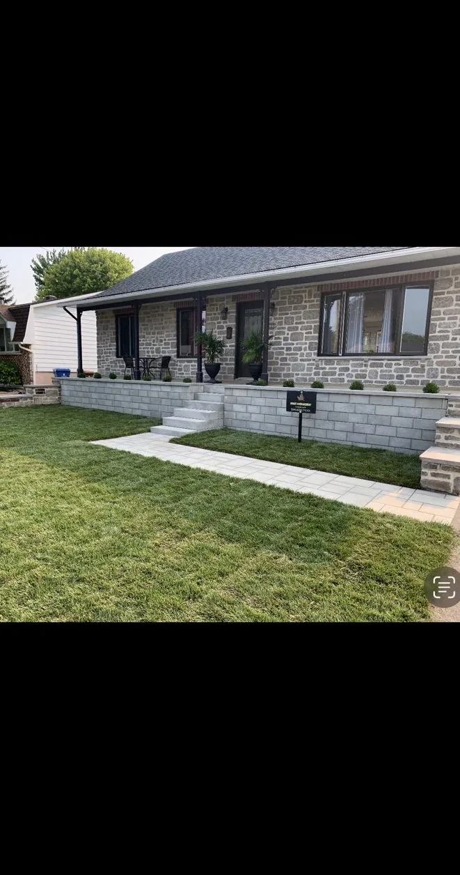 Muret, escalier en blocs, trottoir de pavé et gazon neuf en façade d'une maison