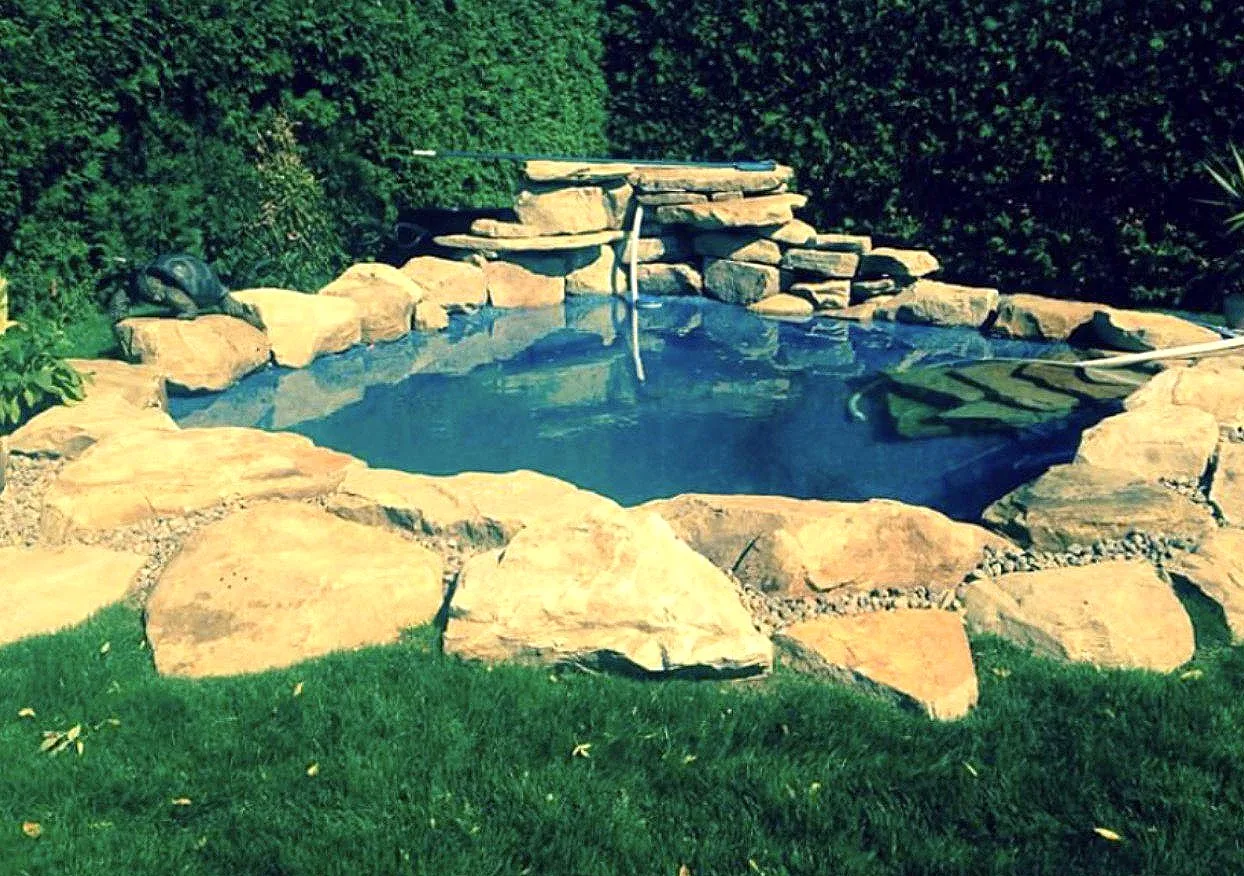 Bassin d'eau avec cascade en pierre naturelle réalisé par Aubry Aménagement Paysagiste