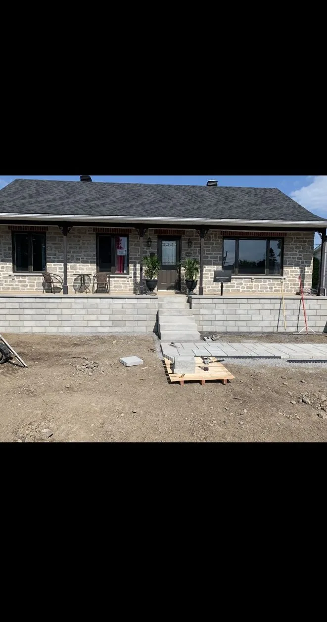 Muret de soutènement et escalier en blocs en construction devant une maison